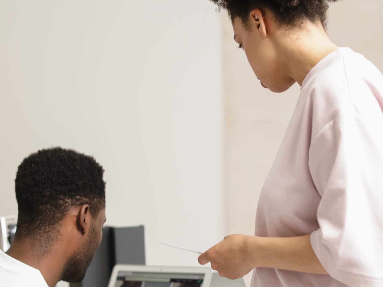 Two colleagues reviewing a set of images together on a laptop in a bright studio