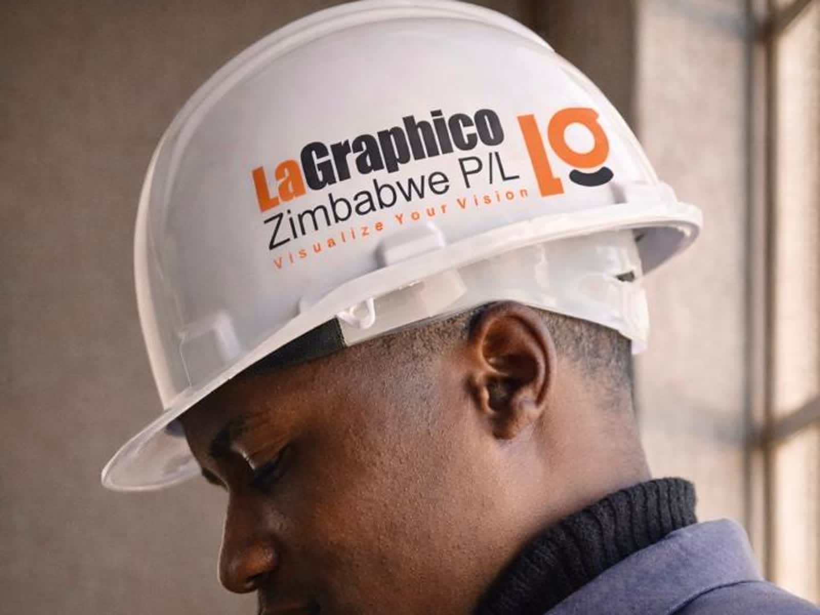 A man wearing a white hard hat branded with the LaGraphico Zimbabwe logo and the tagline Visualize Your Vision