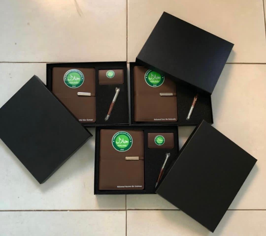 Three brown leather corporate gift sets in black presentation boxes, each with a notebook, card holder and pen branded with the Zimbabwe Halaal Council logo