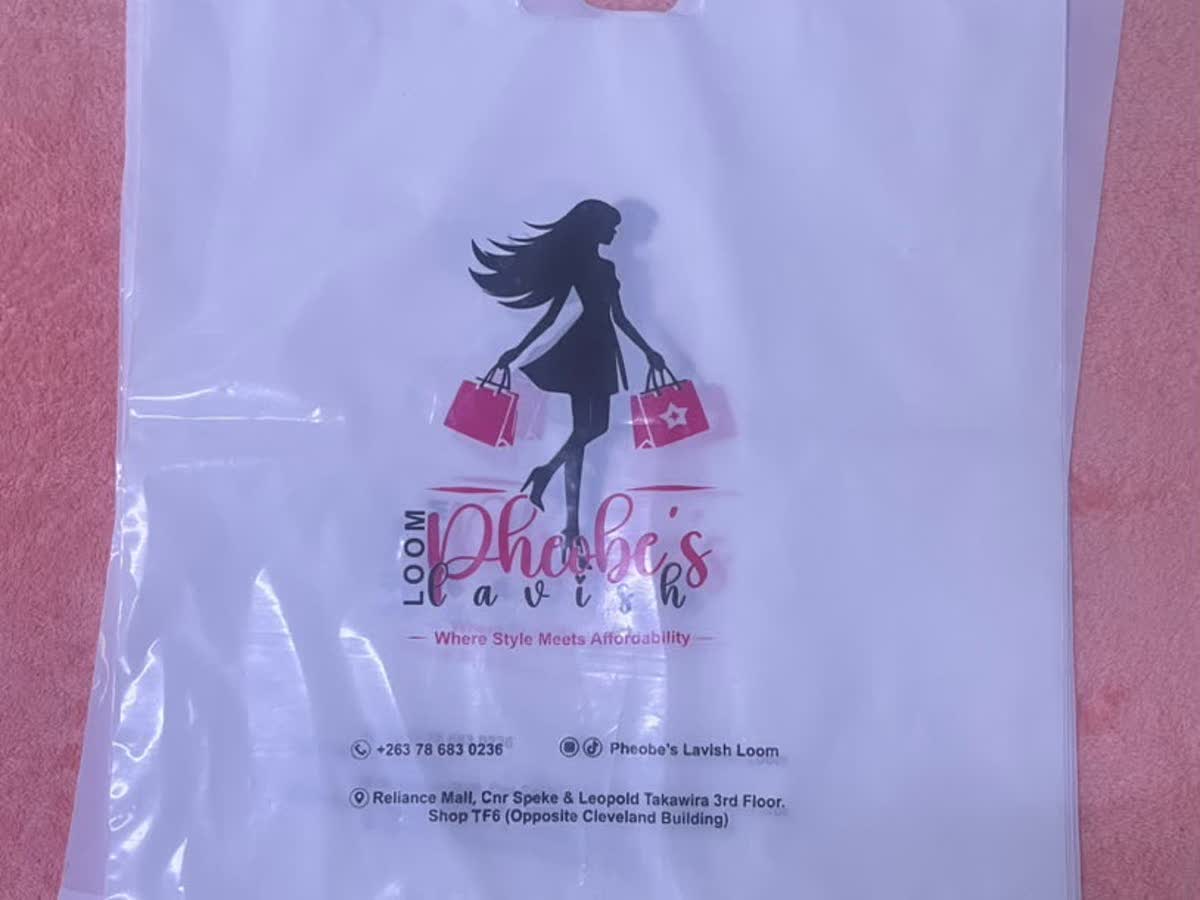 White Phoebe's Lavish Loom shopping bag printed with a pink and black logo and store contact details